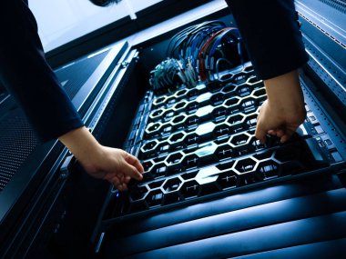 A technician performs maintenance on a server rack in a data center. Cables and hardware components are meticulously organized for optimal performance and security.