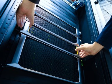 Bir teknisyen bir veri merkezinde sunucu bakımını gerçekleştirir, optimum performans için karmaşık donanım kurulumu ve modern bilgisayar altyapısını vurgular.