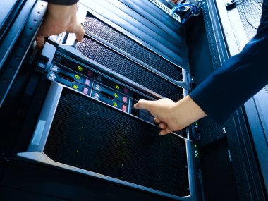 Bir teknisyen, modern bir veri merkezindeki sunucularda, optimum sistem işletimi ve performansı için hassas ve gelişmiş teknoloji sunar..