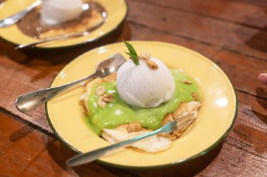 Ağız sulandıran bir tatlı, yeşil bir tepsi ve bir top dondurma, canlı bir tabakta servis edilir, yemek severler ve aşçılar için mükemmeldir..