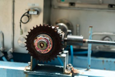 Endüstriyel ekipmanlara monte edilmiş paslı bir teçhizatın yakın plan görüntüsü, bir atölyede makine ve mühendislik ayrıntılarını gösteriyor.