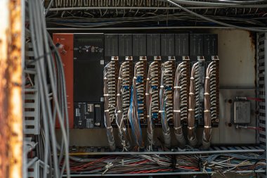 Modern altyapıdaki teknoloji ve endüstriyel bakımı vurgulayarak, çok sayıda kablo ve bağlantıyı gösteren karmaşık bir elektrik kontrol paneli görüntüsü.