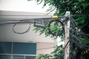 Elektrik kablolarının ve kabloların yoğun bir düzenlenmesi elektrik altyapısının karmaşıklığını gösteren kentsel bir ortamda elektrik direğinin etrafına dolandı..