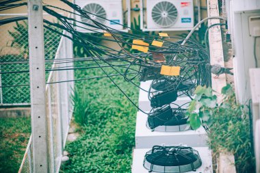 Bu resim, karmaşık kablolar ve açık hava klima birimlerinin yerleşim alanlarındaki kentsel hizmet tesislerinin karmaşıklığını gösteren karmaşık bir düzenini tasvir ediyor..