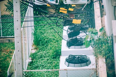 Klima ünitelerinin üstündeki karmaşık kablo ve kabloların yakın plan görüntüsü, kentsel altyapının görüntülenmesi, çevresel etkileşim ve günlük teknoloji.