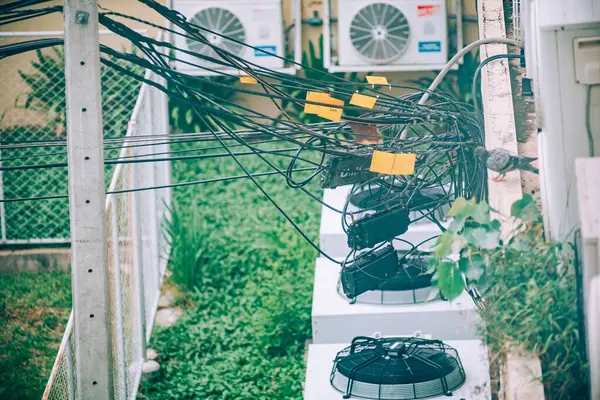 Bu resim, karmaşık kablolar ve açık hava klima birimlerinin yerleşim alanlarındaki kentsel hizmet tesislerinin karmaşıklığını gösteren karmaşık bir düzenini tasvir ediyor..