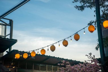 Gece gökyüzünün altında asılı renkli fenerlerin huzurlu bir görüntüsü, sıcak bir parıltı yayıyor ve açık hava toplantıları için rahat bir atmosfer yaratıyor..