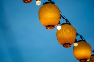 Güzel turuncu fenerler açık bir gökyüzüne asılı, sıcak bir parıltı saçıyor. Kutlama, kültür ve festival ortamı için ideal..