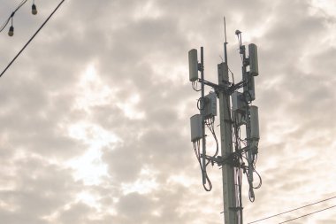 Modern bir baz istasyonu bulutlu bir gökyüzüne karşı dimdik ayakta duruyor ve kırsal ve kentsel alanlarda iletişim sağlanmasında telekomünikasyon altyapısının temel rolünü gözler önüne seriyor..