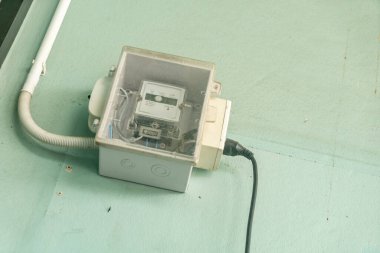 Nane yeşili bir duvara monte edilmiş, enerji kullanımı ölçümünü gösteren temiz bir elektrik sayacı kutusu. Bu kurulum konut elektrik altyapısını vurgular.