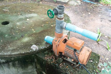 Beton zeminde bir su pompası sistemi, tesisat bağlantıları ve vanaları içerir, tipik olarak sulama ya da dış ortamlarda drenaj için kullanılır..