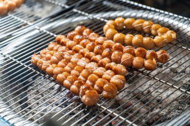 Tel askıya dizilmiş leziz ızgara atıştırmalık toplar, altın dokularını ve dumanlı cazibelerini sergiliyorlar, sokak yemekleri severler ve aşçılar için mükemmel..