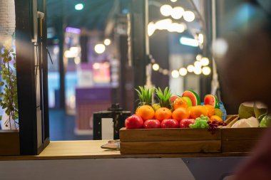 Kalabalık bir pazarda canlı bir taze meyve gösterisi, renkli elmalar, portakallar ve davetkar bir ortamda diğer tropik lezzetler sergileniyor..