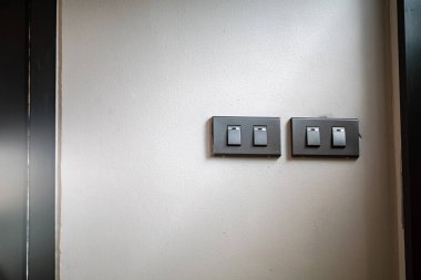 Bu resim, çağdaş iç estetiği geliştiren parlak bir tasarımı gösteren, minimalist bir duvara monte edilmiş modern ışık anahtarlarını içerir..