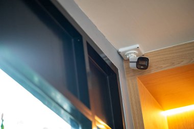 Modern bir güvenlik kamerası şık bir odada duvara monte edilmiş, güvenlik için gerekli güvenlik teknolojisinin yanı sıra çağdaş tasarımı da sergiliyor..