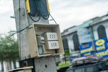 Bir elektrik bağlantı kutusunun kentsel bir ortamda elektrik direğine monte edilmesi, elektrik prizlerinin gösterilmesi ve şehrin arka planına elektrik kablolarının bağlanması..