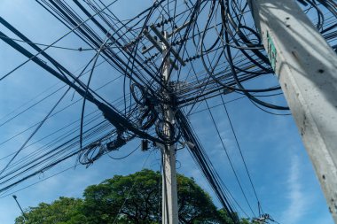 Parlak mavi gökyüzüne karşı karışık elektrik kabloları ve elektrik hatlarının dinamik bir bakış açısı. Bu görüntü, karmaşık güzelliğiyle şehir altyapısını yakalıyor..