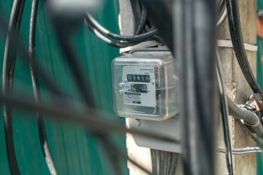 Bir binaya bağlı bir elektrik sayacına yakın çekim, enerji okumalarını ve kablolarını gösteriyor. Bu görüntü teknoloji ve altyapının entegrasyonunu yakalar.