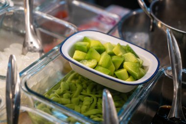 Bir kasede servis edilen taze doğranmış yeşil sebzelerin canlı bir gösterisi, her yemeğe ya da yemeğe renk ve besin katmak için mükemmel..
