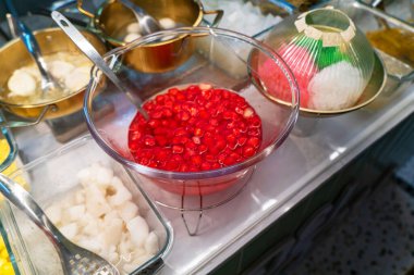 Renkli malzemelerin canlı bir gösterisi, şurupta bir kase kırmızı kiraz, tatlandırıcı tatlılar ve mutfak sunumları için mükemmel..