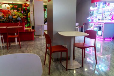 Rahat bir kafe seti gösterişli masalar ve renkli sandalyeler içerir, sosyalleşme ve rahatlama için mükemmeldir. Canlı dekor atmosfere eğlenceli bir dokunuş katıyor..