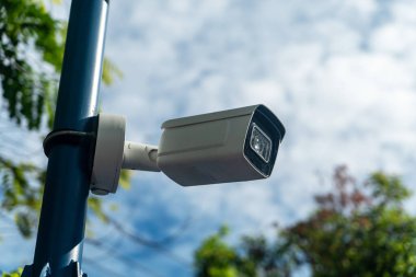 Bir direğe monte edilmiş modern bir güvenlik kamerası açık hava ortamını yakalıyor, kentsel alanlarda güvenliği ve güvenliği artırıyor. Etkinlikleri izlemek için ideal.