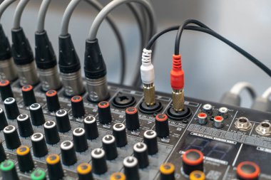 Çeşitli düğmeler, girdiler ve kablolar içeren bir ses karıştırıcının yakın görüntüsü. Müzik ve kayıt ortamlarında ses ekipmanlarını sergilemek için mükemmel..