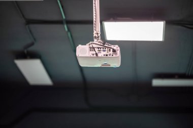 Modern bir çalışma alanında asılı tavana monte edilmiş bir projektör, zarif ışıklandırma ve temiz tasarım ile sunumlar ve toplantılar için gerekli teknolojiyi sağlıyor.