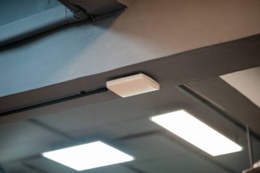 Modern bir tavan lambası endüstriyel bir iç mekanda, odanın estetik çekiciliğini ve işlevselliğini arttıran yumuşak bir parıltı yayar..