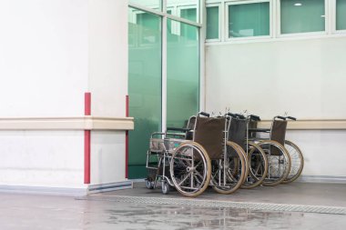 Temiz bir hastane koridoruna yerleştirilmiş bir sıra boş tekerlekli sandalye, sağlık ortamında erişilebilirlik ve destek temaları vurgulanıyor.