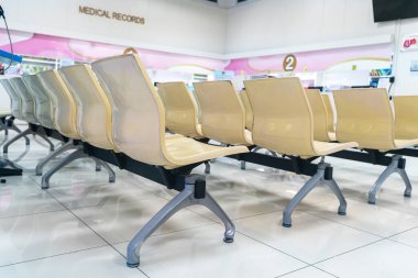 Bu resim modern bir bekleme alanını gösteriyor. Gösterişli, plastik sandalyeler sağlık hizmetleri ortamında konfor için tasarlanmış. Geniş iç mekan temiz ve rahatlatıcı bir atmosfer sağlıyor..