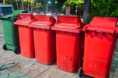 Canlı bir şehir ortamında renkli geri dönüşüm kutularından oluşan bir sıra. Bu çöp konteynırları atık yönetimi ve temizliği teşvik ederek toplumda geri dönüşümü teşvik ediyor.