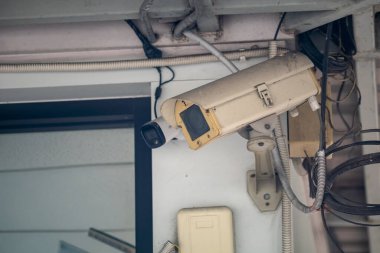 Duvara monte edilmiş bir güvenlik kamerasının yakından görüntüsü, güvenlik özelliklerini ve etkinlikleri izlemek için kapalı bir ortamda kurulum unsurlarını gösteriyor..