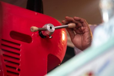 Kırmızı mutfak aletini kullanan bir elin yakın plan görüntüsü, mutfak hazırlıklarında kullanılan manüel mekanizma ve zanaatkarlığı gösteriyor.