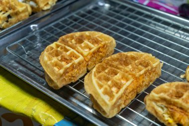 Metal bir rafta sergilenen lezzetli gözlemeler, nefis bir altın rengi ve çıtır çıtır dokuları sergiliyor, kahvaltı ve atıştırmalık için mükemmel..