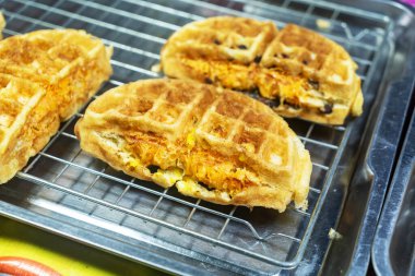 Bu resimde lezzetli ve lezzetli malzemelerle dolu çıtır bir waffle var. Kahvaltı için mükemmel ya da lezzetli bir aperatif seçeneği olarak..