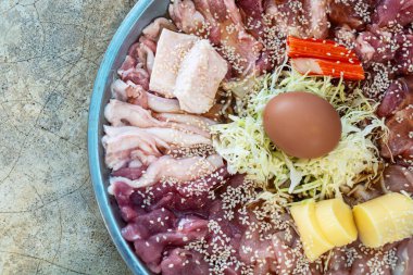 Çeşit çeşit et, yumuşak yumurta, sebze ve susam tohumlarının da dahil olduğu canlı, dairesel bir tepsi. Mutfak araştırmaları için mükemmel..