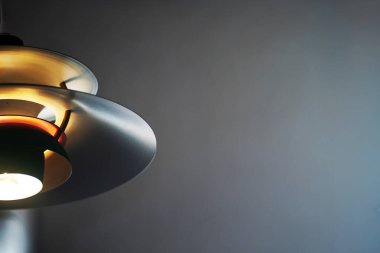 Modern bir kolye lambasının yakın plan görüntüsü zarif çizgiler ve yumuşak ışıklandırma sergiliyor. Bu resim iç dekorasyon ilhamı için çağdaş tasarımı vurgular.