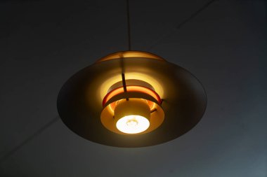 Bu resim, iç mekanlara zarafet ve sıcaklık katan eşsiz bir tasarıma sahip modern bir kolye aydınlatma armatürünü sergiliyor. Çağdaş dekor için ideal.