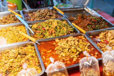 Bir market tezgahında çeşitli Asya sokak yemekleri sergileniyor. Renkli düzenlemeler çeşitli lezzet ve malzemeler sergiliyor..