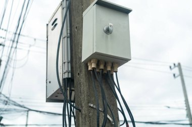 Tahta bir direğe monte edilmiş, çeşitli kablolar ve kablolar sergileniyor. Bu resim şehir altyapısını ve kurulumunu temsil eder.