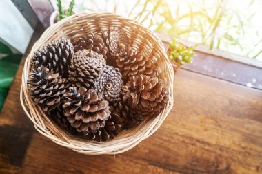 A beautiful arrangement of natural pine cones displayed in a rustic basket on a wooden table, perfect for home decor and seasonal decoration ideas.