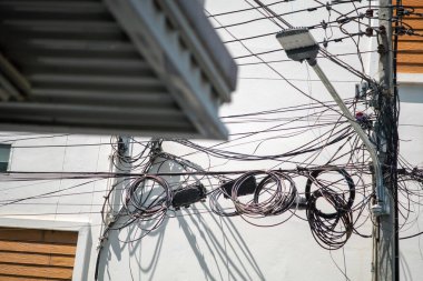 A complex arrangement of tangled wires and cables draped over an urban utility pole, showcasing the intricate details of city infrastructure and utility systems.