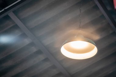 A hanging pendant light illuminates a rustic interior space, casting a warm glow and creating a cozy atmosphere. Ideal for home decor inspiration.