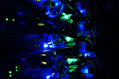Close-up view of network cables and illuminated lights within a server rack, showcasing the intricate technology of modern data infrastructure.