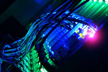 An intricate view of illuminated cables and wires in a data center, showcasing vibrant blue and green lights. This image captures the essence of modern technology and network infrastructure.
