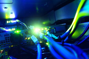 Bir sunucu içindeki aydınlatılmış ağ kablolarının yakın görüntüsü, modern dijital ortamda canlı mavi ve yeşil LED ışıklar sergiliyor.