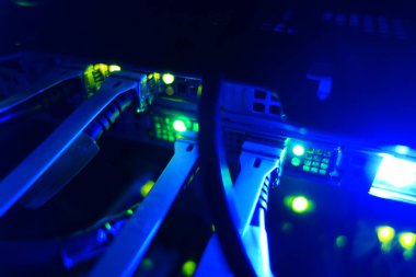 Bir sunucu odasındaki ağ kablolarının ve parlayan ışıkların yakın görüntüsü, dijital altyapıdaki teknoloji, bağlantı ve makine işlevselliğini gösteriyor.