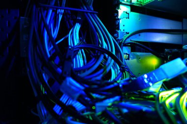 A vivid close-up of colorful network cables tangled within a server environment, showcasing technology's intricate connections and electric hues.