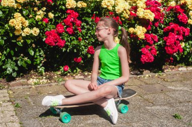 Parkta güneşli bir günde kaykaylı genç bir kız.